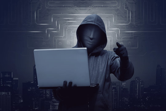 Hacker man with mask holding laptop while appoint