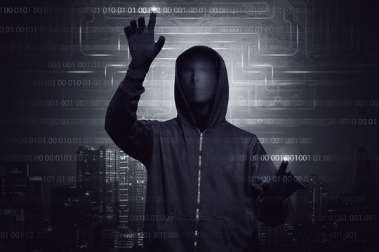 Hooded hacker with mask using virtual screen to hacking system security