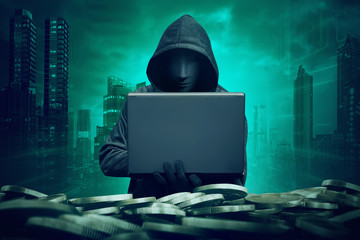 Hooded hacker with mask using laptop to hacking bank