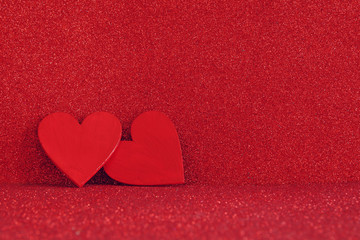 Wooden red hearts on red shiny background
