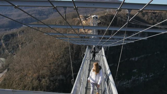 Woman walk thru high bridge over the canyon at SkyPark AJ Hackett Sochi
