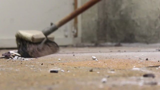 Broom Sweeping across dusty unfinished basement floor