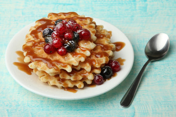 Baked waffles with fresh berries on a blue wooden background. Breakfast.