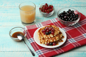 Baked waffles with fresh berries on a blue wooden background. Breakfast.
