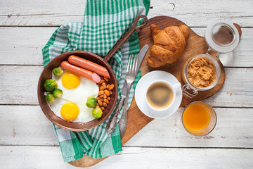 Breakfast - egg, sausage, haricot,  Brussels sprout, toasts, coffee and juice on a table. Selective focus. The top view. Copy space