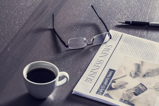Newspaper with eyeglasses on wooden table