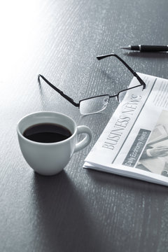 Newspaper with eyeglasses on wooden table