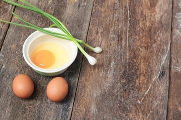 Raw egg in a bowl selective focus and onion on wooden table