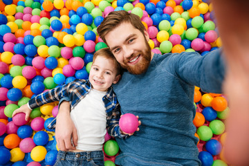 Son with dad taking selfie in colorful balls pool