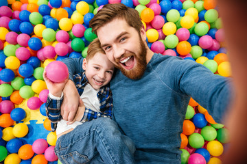 Fototapeta na wymiar Dad and son talking selfie at pool with colorful balls