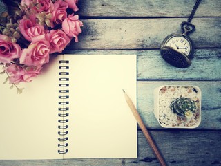Notebook, pencil, pocket watch, cactus and flower on old wood table