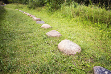 Way from  cobble-stones on green herbs a background