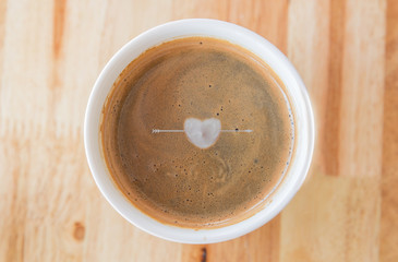 Heart in cup of coffee with in a white cup on wooden background.