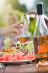 Focus on a picnic table, at background friends drinking wine