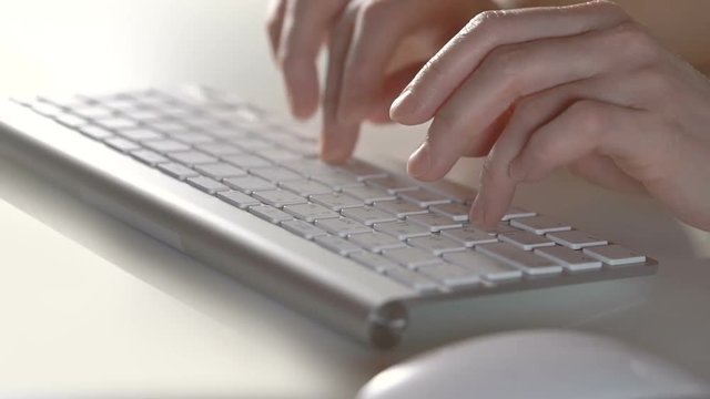 Female hands typing on the silver keyboard. Close view