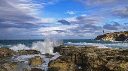 Sea waves crashing against rocks near the lighthouse