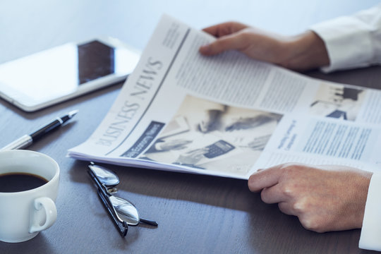 Woman reading newspaper on table