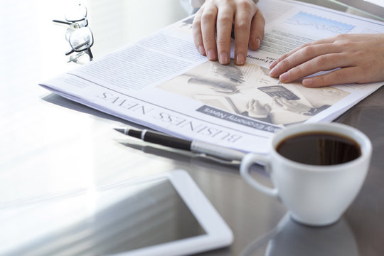 Woman reading newspaper on table