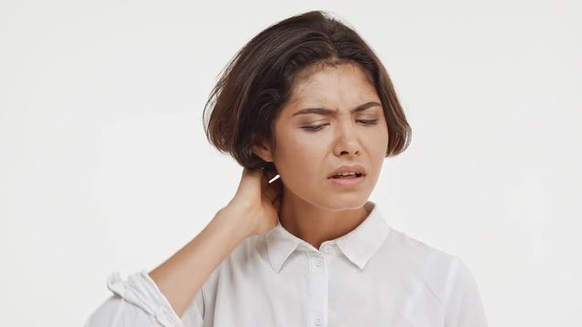 Thoughtful young beautiful brunette east asian female in shirt standing in hesitation on white background in slowmotion