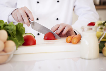 Obraz na płótnie Canvas Chef Cutting a Tomato