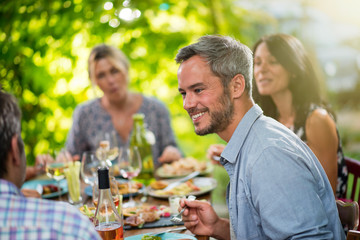 Group of friends having fun around a meal on a terrace in summer