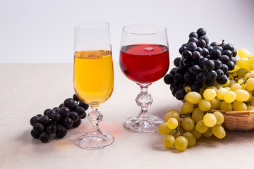 Wine and grapes. White and red wine in glasses on light marble b