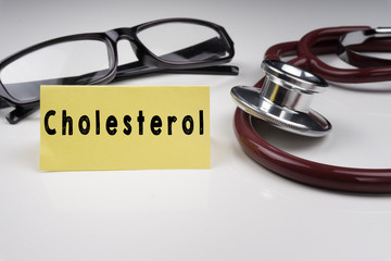 Sticky notes written with CHOLESTEROL and stethoscope on white background. Medical Concept.