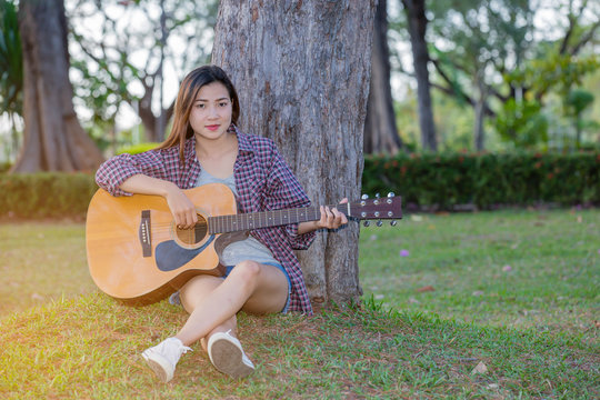 Young asian girl in forest with guitar in the garden