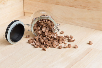 Chocolate cereal cornflakes spilling to the wood surface