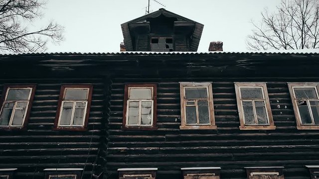 Old wooden house with black windows. Nobody inside. Abandoned house in disrepair with boarded-up windows in Pereslavl-Zalessky city, Russia