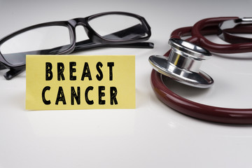 Sticky notes written with BREAST CANCER and stethoscope on white background. Medical Concept.