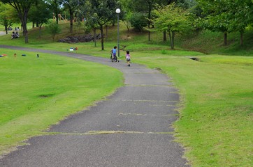 公園で自転車に乗る男の子を追いかける女の子