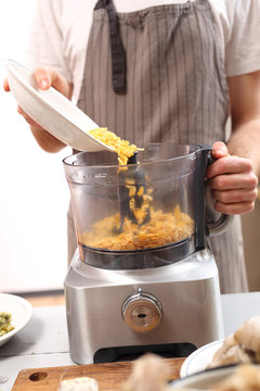Kucharz miksuje warzywa w robocie kuchennym.
Pomocnik kuchenny , gotowanie potrawy.