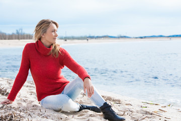 femme en hiver assise sur la plage regardant l'horizon