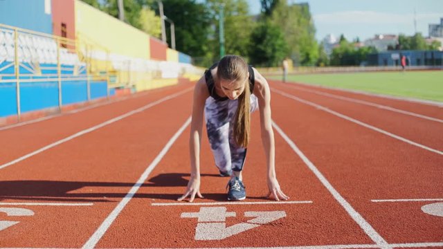 Female athlete getting ready to blast off outdoors at the stadium
