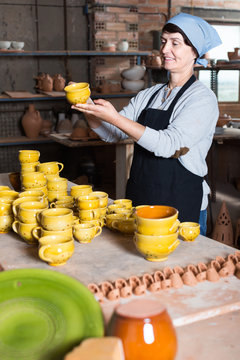 elderly woman with cups at pottery workshop.