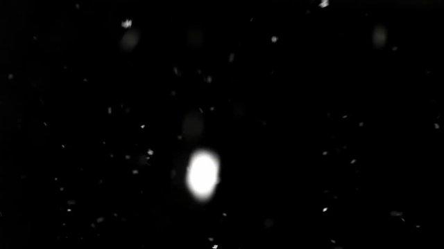 White particles on a black background fly from top to left