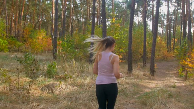 4K footage of beautiful slim woman running at autumn forest
