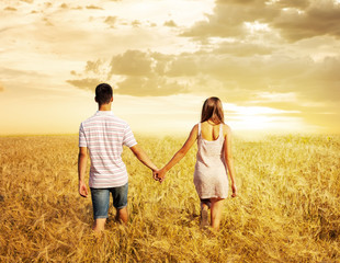 love couple walking in sunset field holding hands