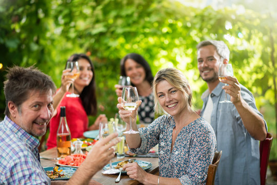 Group of friends toasting during a party on a terrace in summer
