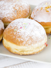 donuts with frosting and powdered sugar on a platter