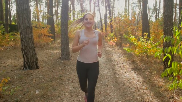 Slow motion closeup shot of young active woman with ponytail exercising at autumn forest