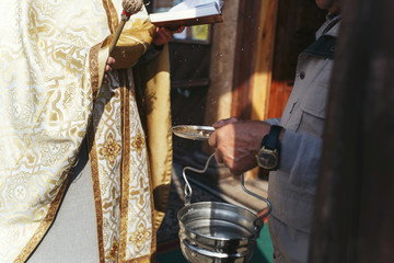 Man with steel plate with wedding rings and bowl with holy water