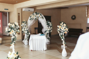 Little white table stands before white wedding altar made of vei