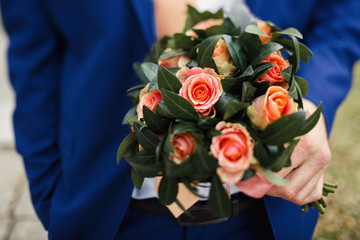 Close-up of pink rose bouquet held by man in bright blue suit