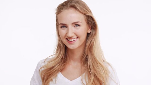 Young beautiful Caucasian blonde girl smiling at camera and showing ok with two thumbs on white background