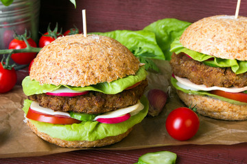 Homemade hamburgers with fresh vegetables on wooden background