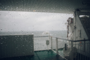 Blurred image of ferry deck through window, stormy weather