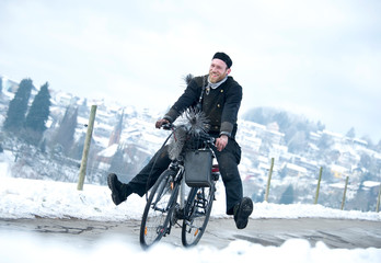 Schornsteinfeger fährt mit Fahrrad durch winterliche Landschaft