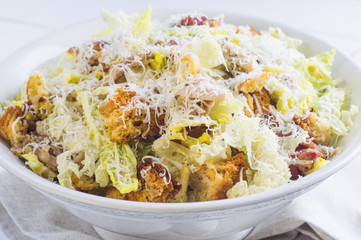 Caesar Salad with on white plate. Delicious Caeser salad with croutons, roasted chicken meat, parmesan cheese and cos lettuce, with sauce, healthy recipe, close-up. Healthy food.